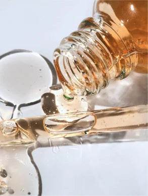 Frasco de gel antioxidante ginkgo vazando sobre superfície refletiva, destacando sua textura suave e iluminada